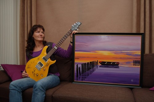 Anna Schat-Vanger with her painting and the guitar she won